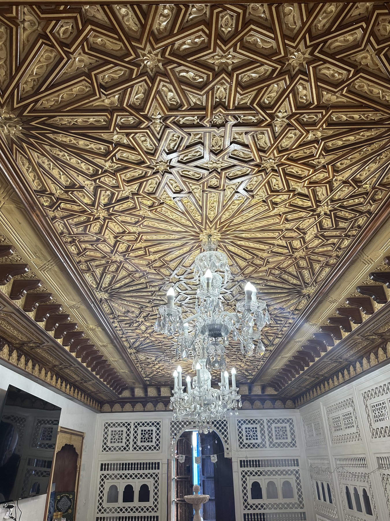 Plafond géométrique sculpté avec lustre au centre du salon